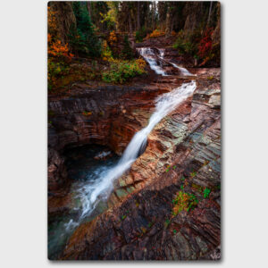 A waterfall cascading down red rocks in Glacier National Park